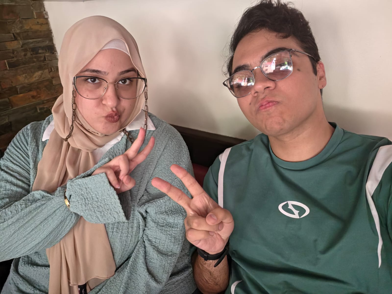 Touqa and Mohamed wearing green and making peace signs