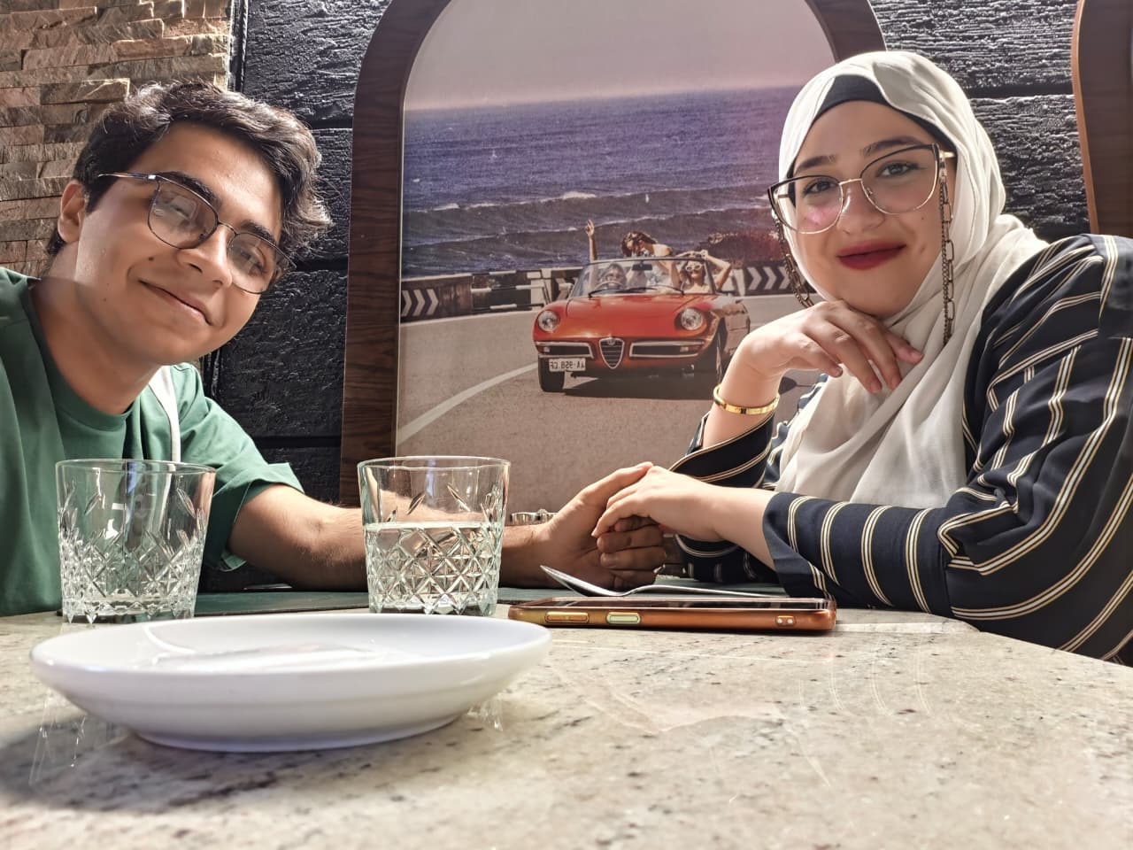 Touqa and Mohamed holding hands over a dining table